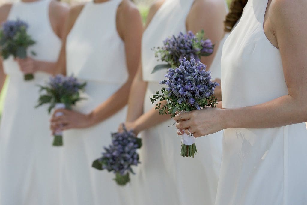 A group of women holding purple flowers in their hands.
