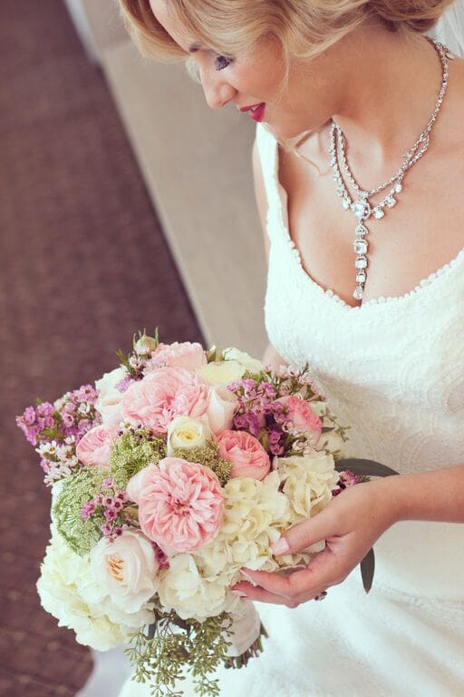 A bride holding her bouquet of flowers in front of her face.