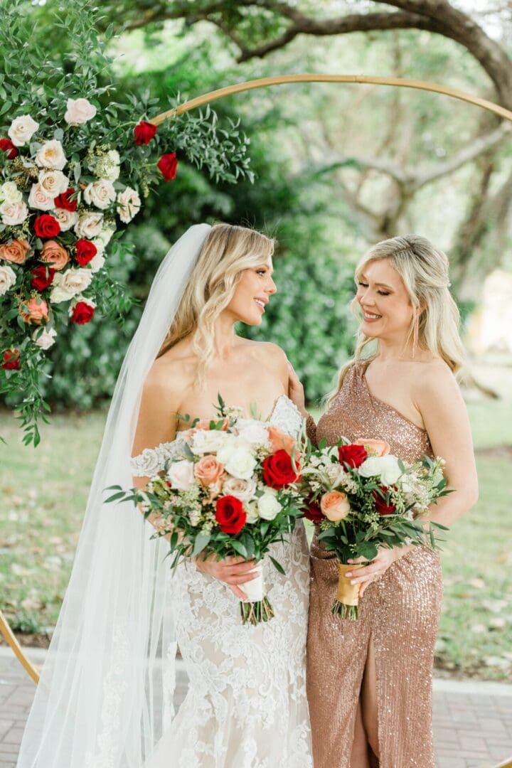 Two women standing next to each other holding bouquets.