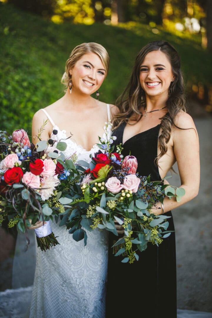 Two women holding bouquets of flowers posing for a picture.