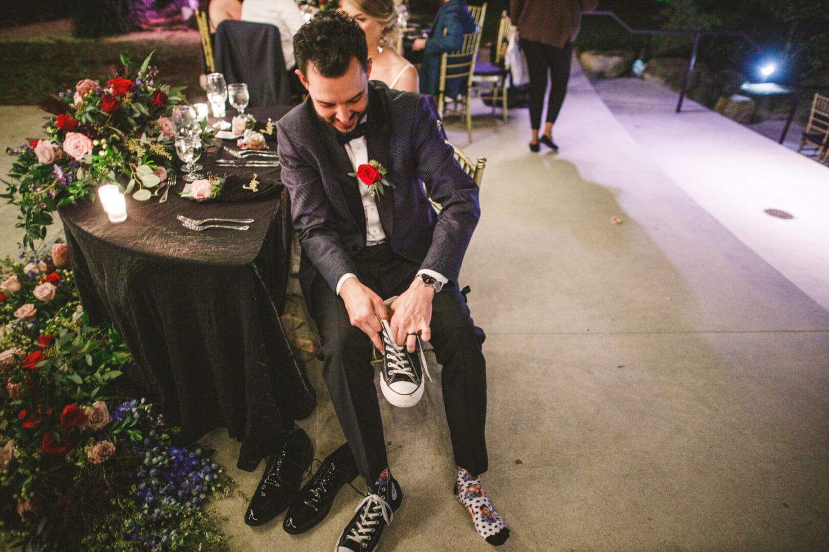 A man in a suit and tie tying his shoe.