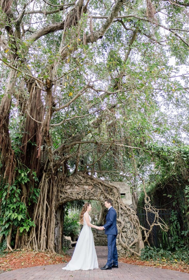 A couple is holding hands in front of a tree.