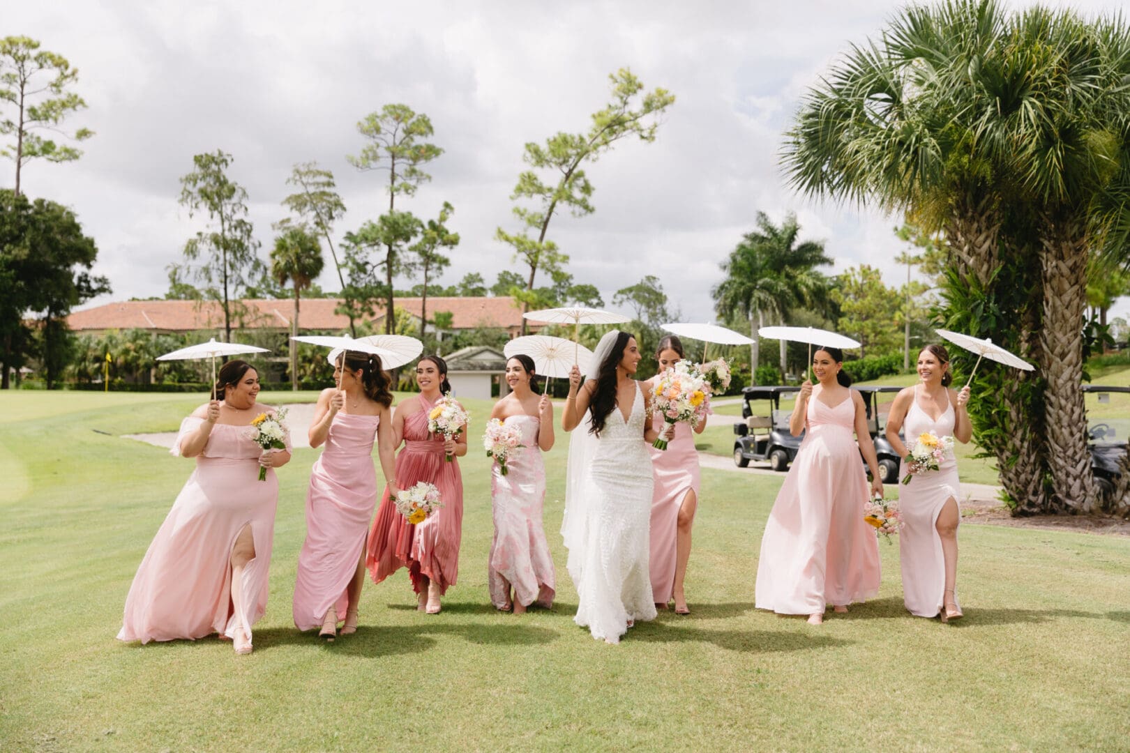 A group of women in pink dresses on the grass.