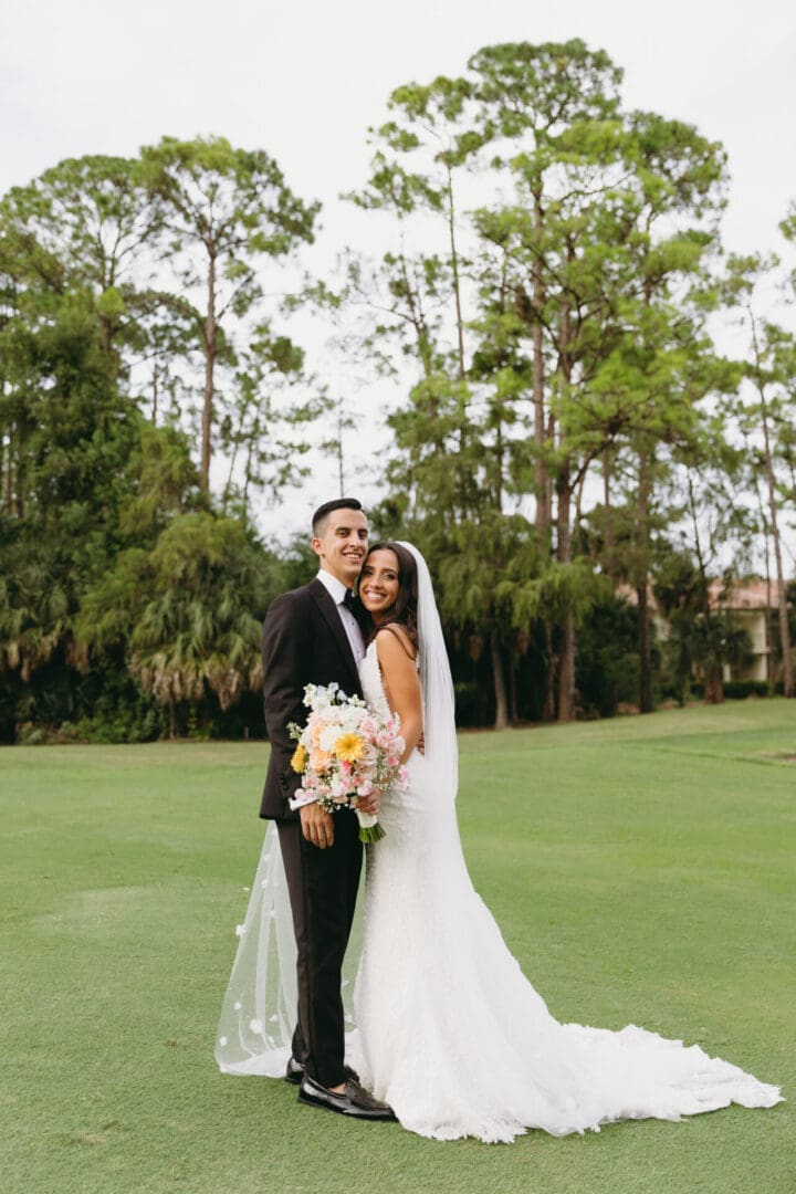 A bride and groom pose for a picture on the golf course.